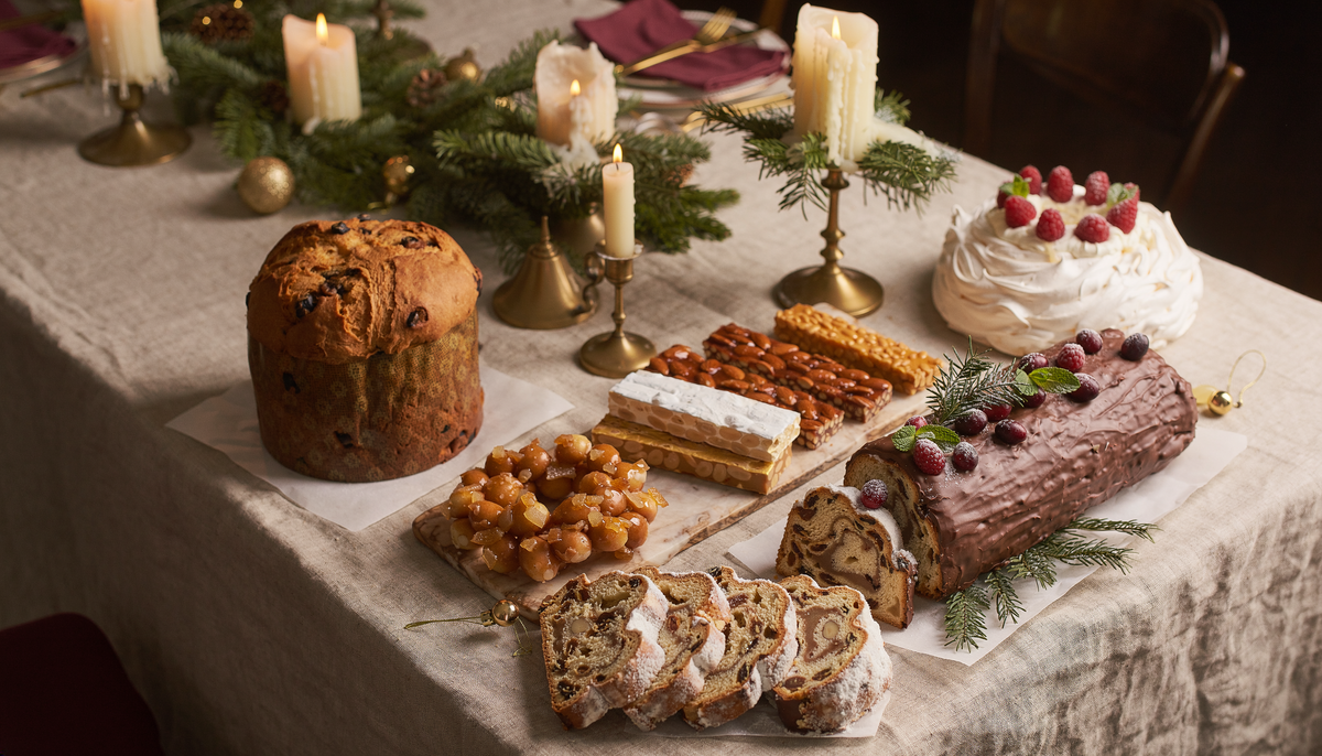 Výběr tradičních a moderních vánočních dezertů z různých částí světa na svátečním stole
