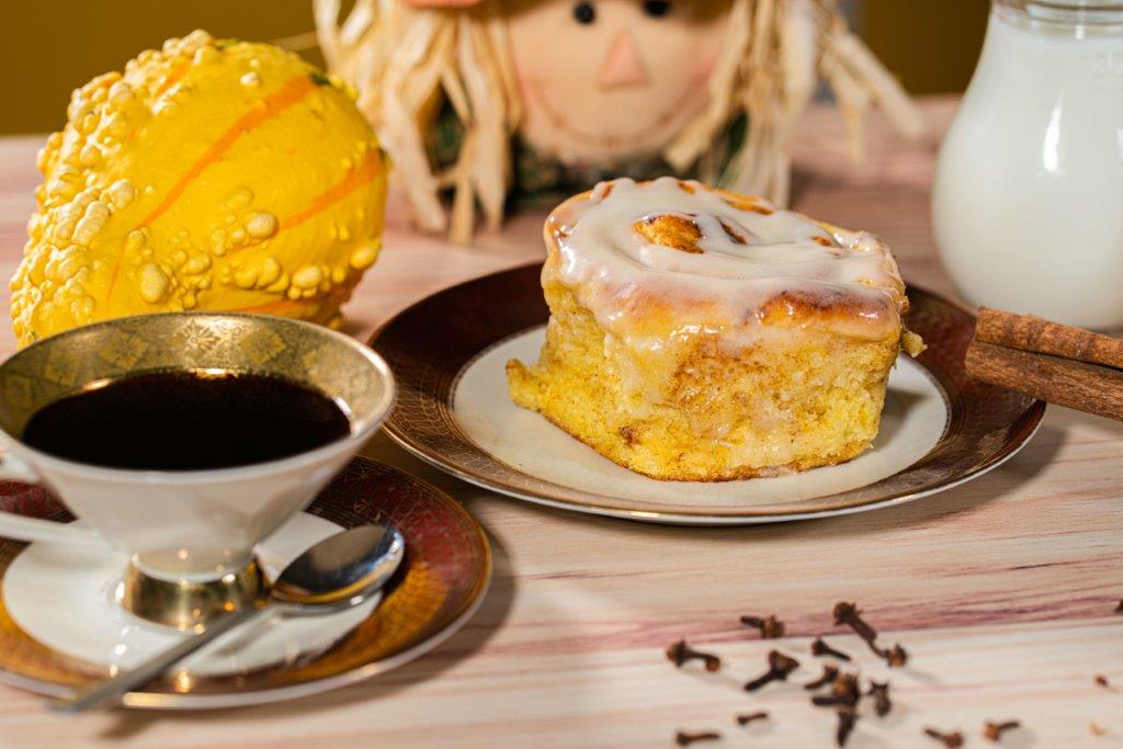 Dýňová skořicová rolka s mascarpone polevou v podzimní dekoraci s kávou, mlékem a skořicí