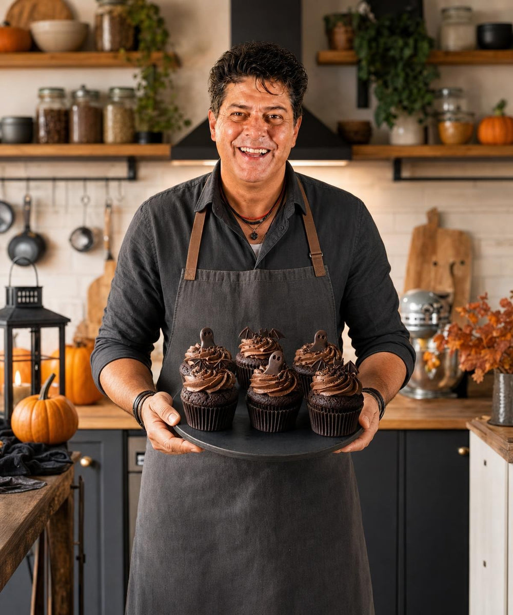 Majkl drží hotový pokrm Čokoládové cupcakes s halloweenskou dekorací a usmívá se do kamery.