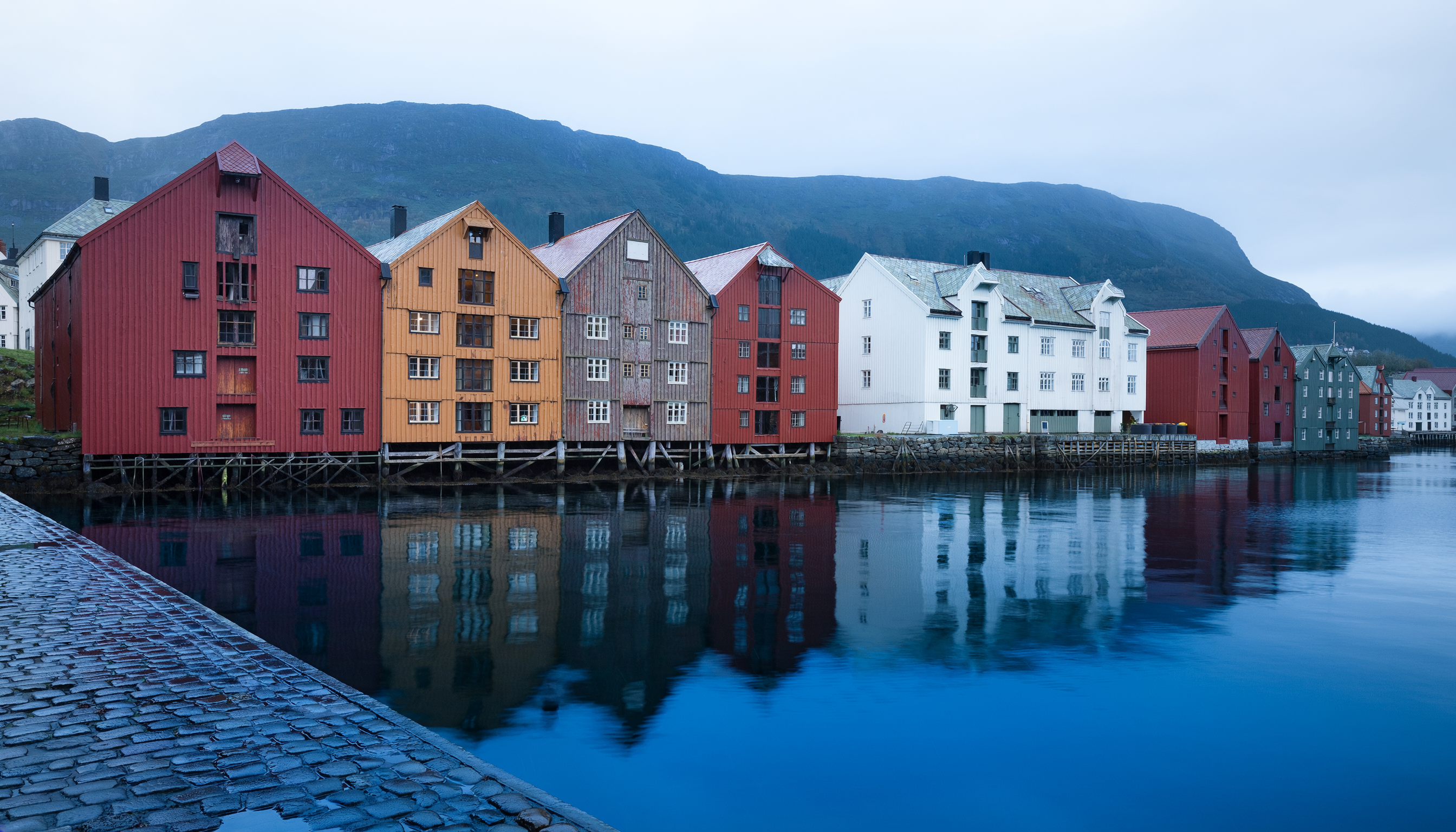 Dřevěné domy přístavu Bergen nad klidnou vodou za podzimního dne